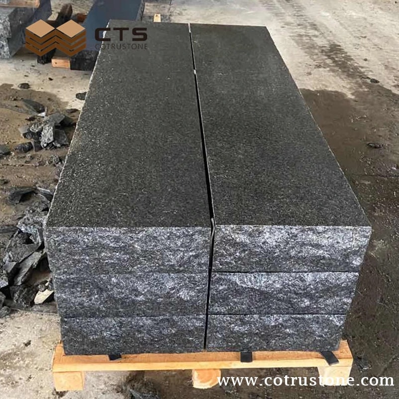 Dark granite step components stacked on a pallet with textured front edges