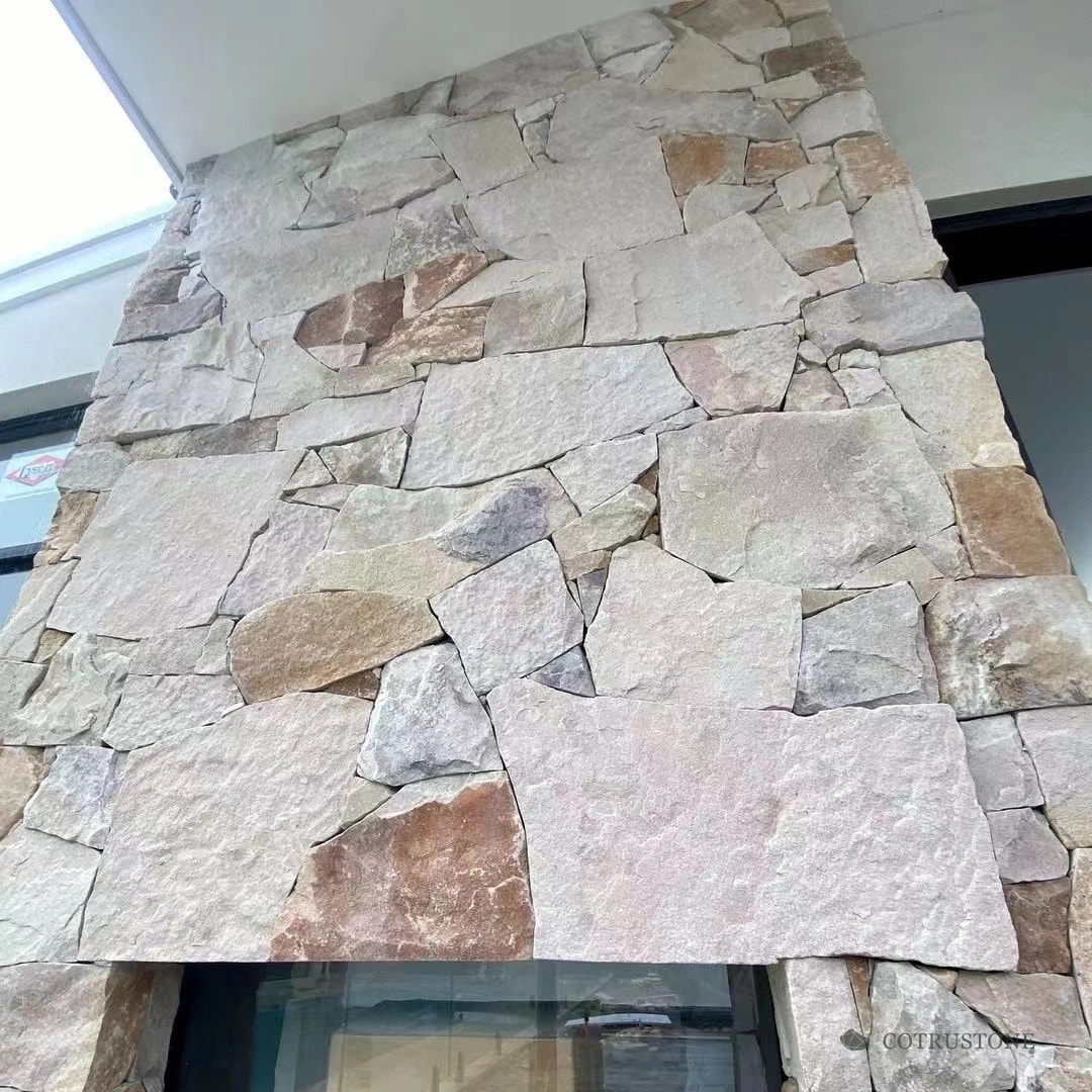 Wall faced with irregular pale sandstone pieces and varied natural tones