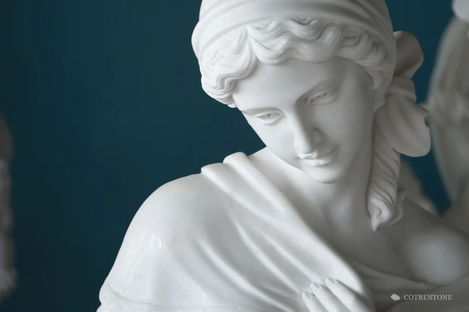 Close view of a white stone sculpture showing the carved face, hair and drapery