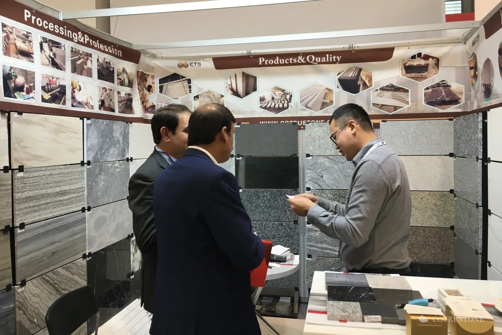 Conversación en el stand de Cotrustone en Italia, rodeado de muestras de piedra