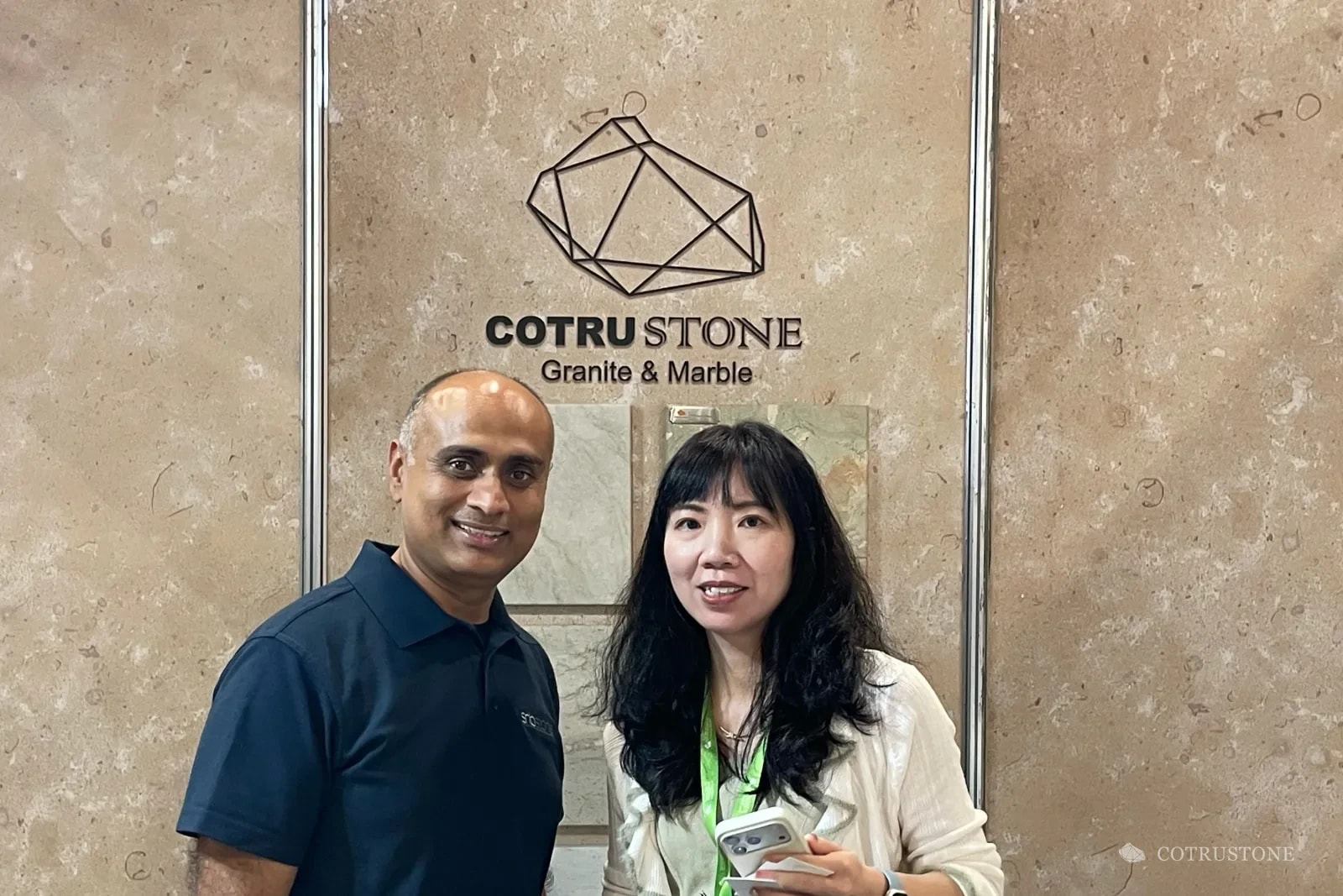 Dos personas junto a las muestras de piedra y el logotipo de Cotrustone en una feria de Sídney
