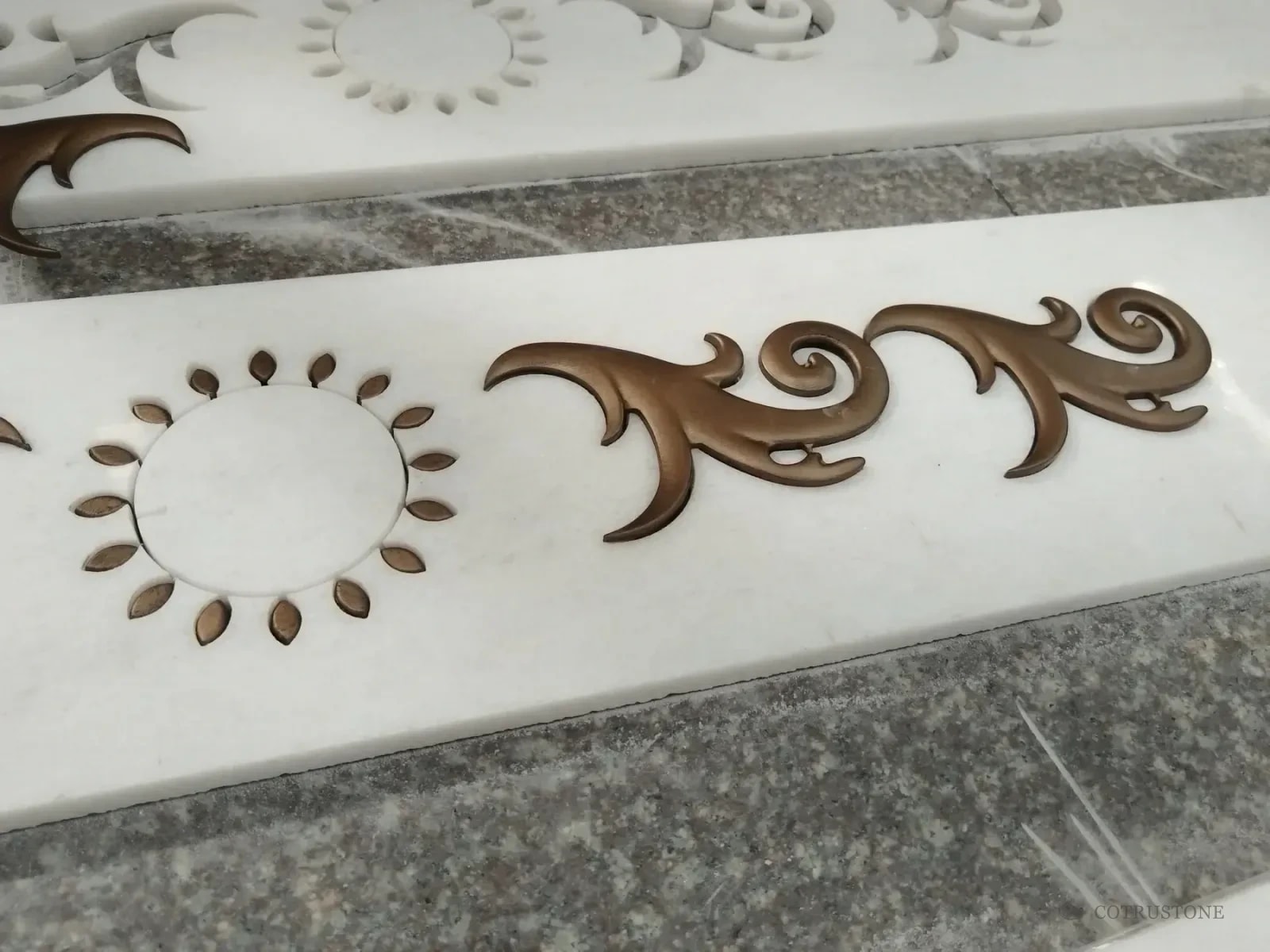Metal-inlaid marble risers with scroll and rosette details