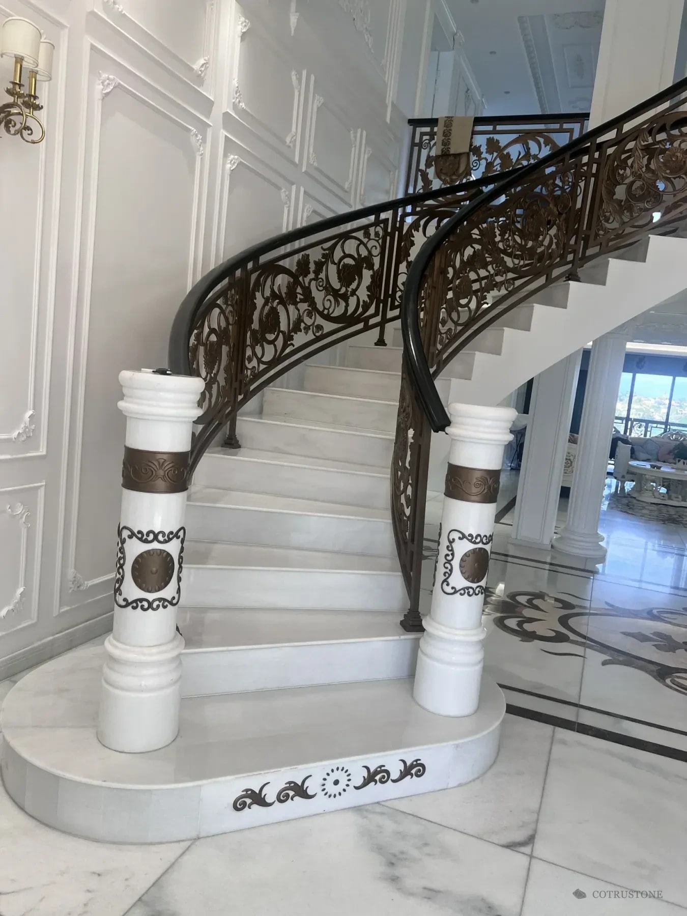 Curved stone stair with decorated newel posts and marble flooring photographed during a client visit
