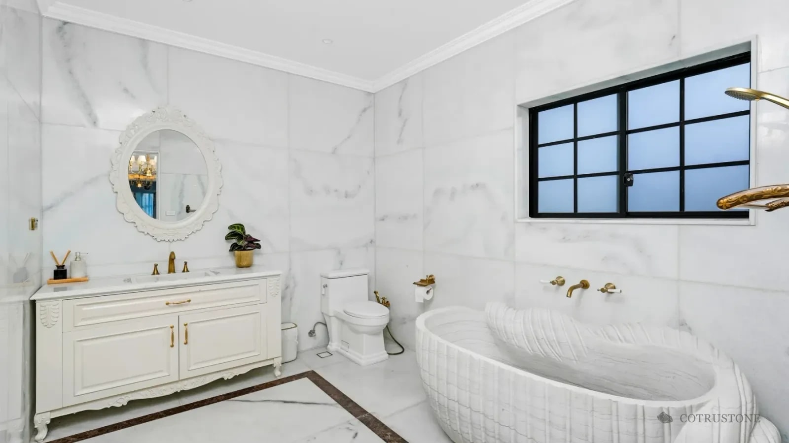 Sculpted stone bathtub alongside marble wall and floor surfaces in a bathroom