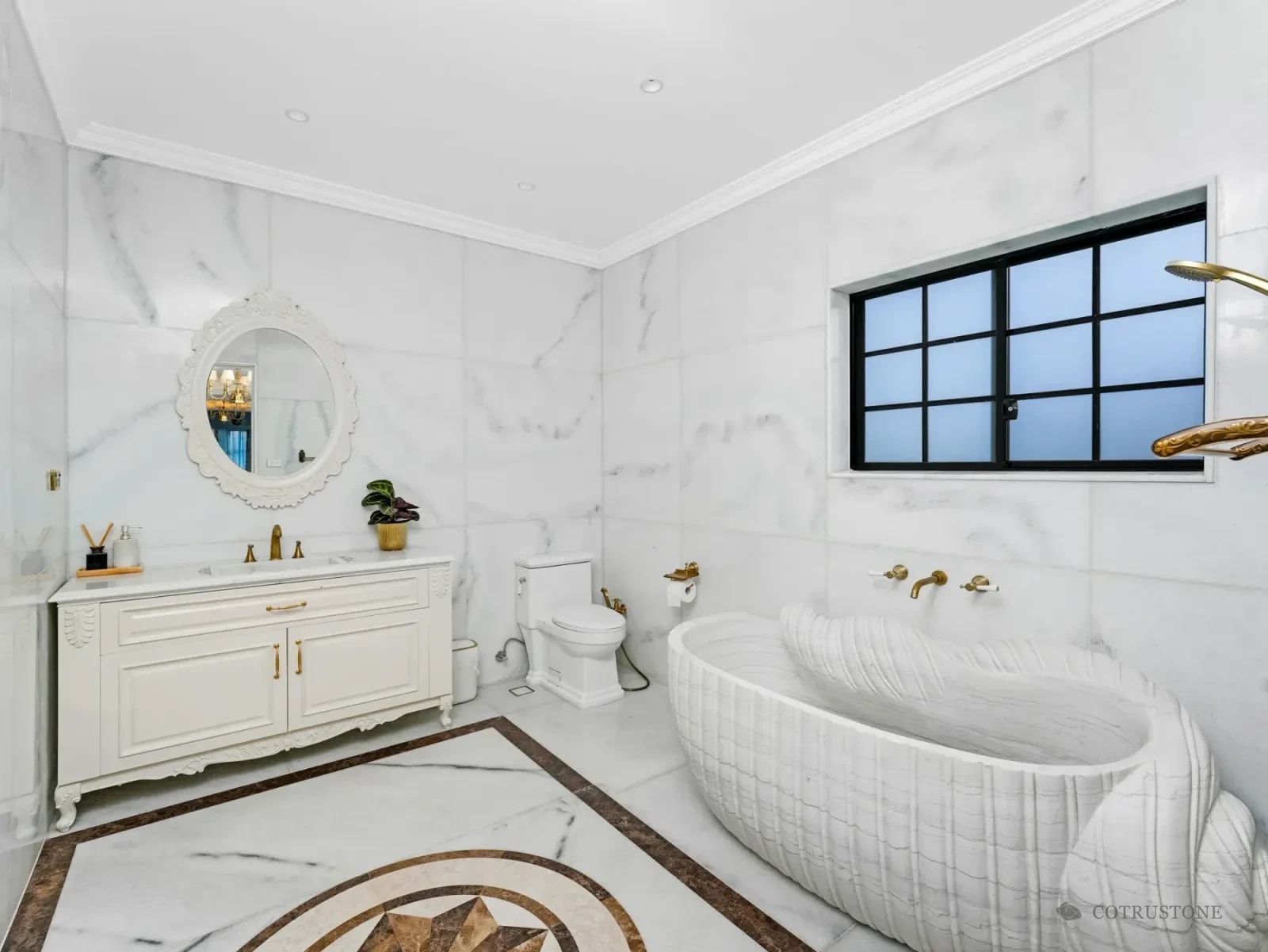 Sculpted stone bathtub alongside marble wall and floor surfaces in a bathroom
