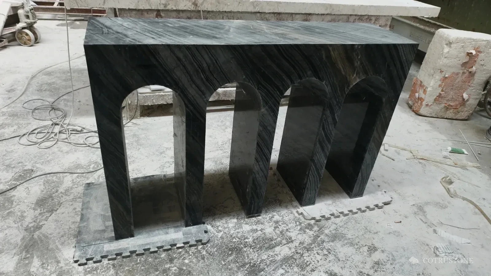 Dark veined stone console with three arch openings in the workshop