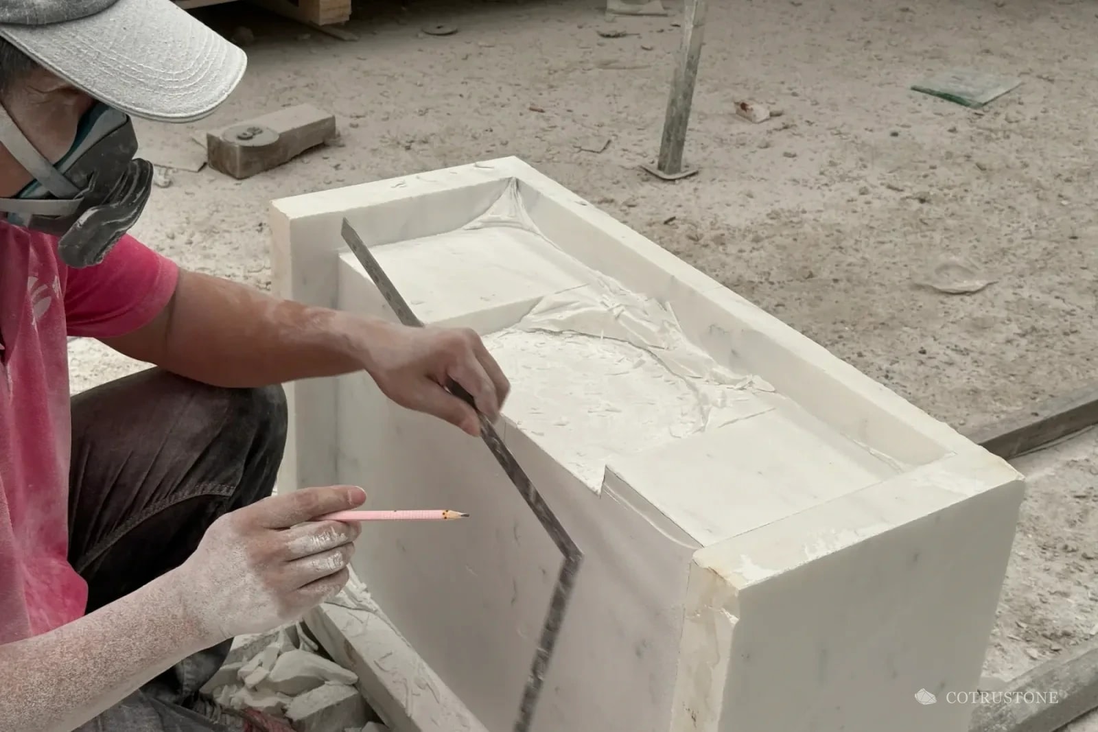 Stoneworker checking a carved profile with a square and marking pencil