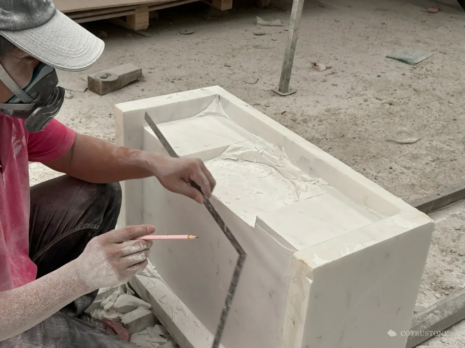 Stoneworker checking a carved profile with a square and marking pencil