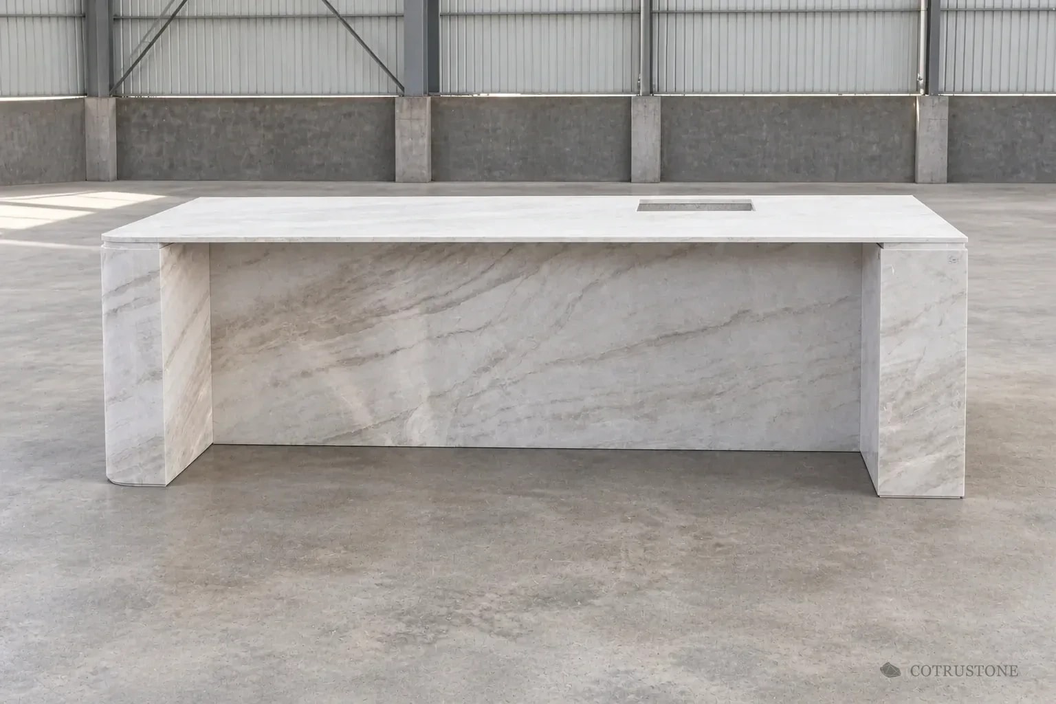 Natural stone island with waterfall ends, a recessed panel and countertop opening