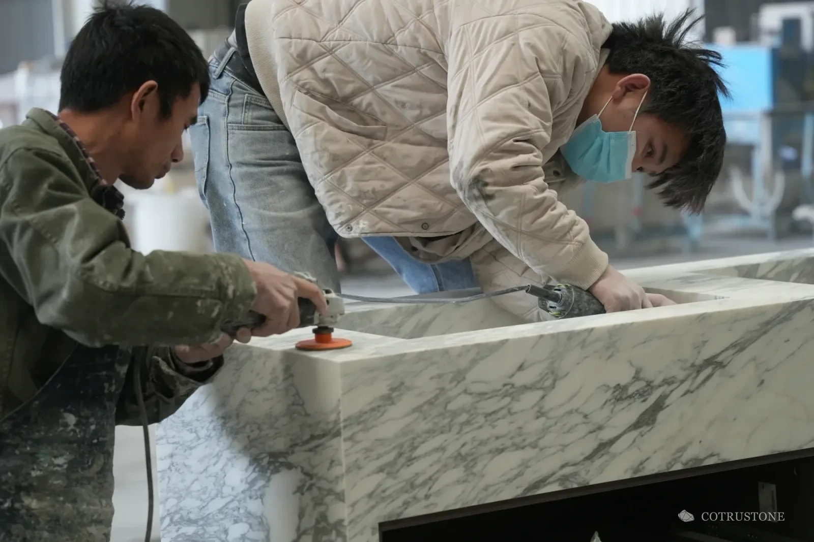Two stone workers finishing a veined stone basin at the workbench