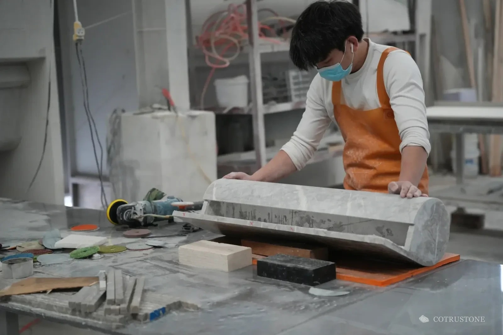 Stone worker handling a long rounded basin on a workshop finishing bench