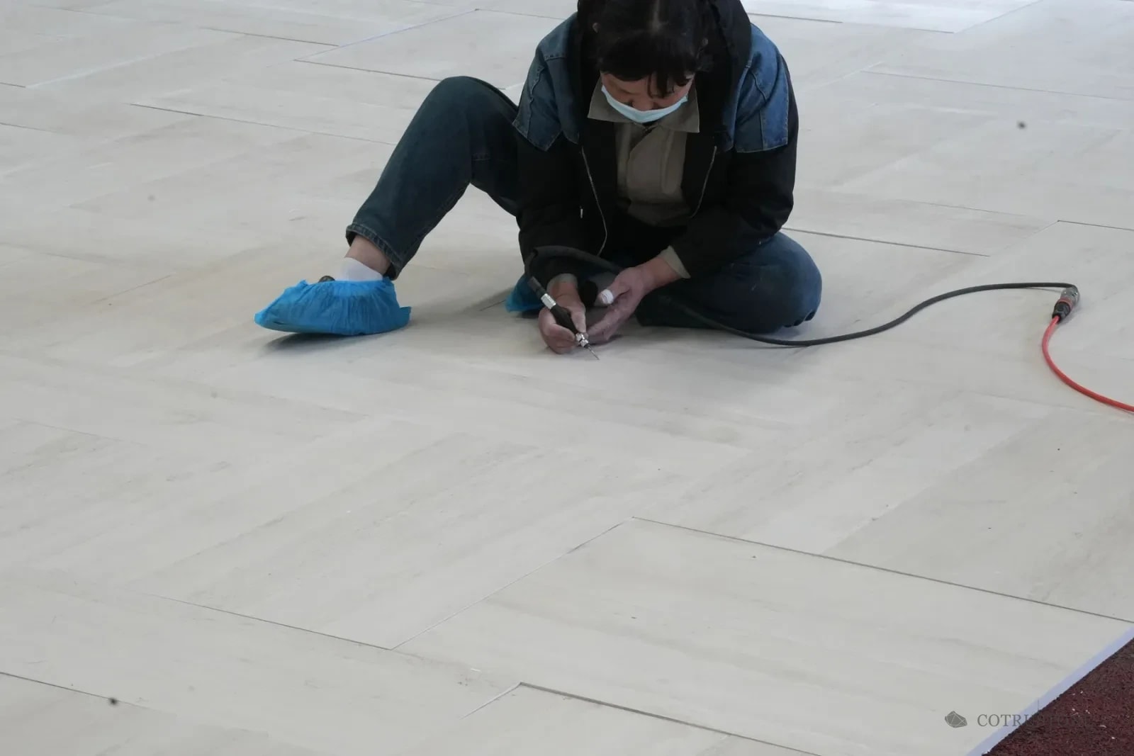 Worker using a small handheld tool on laid-out stone panels