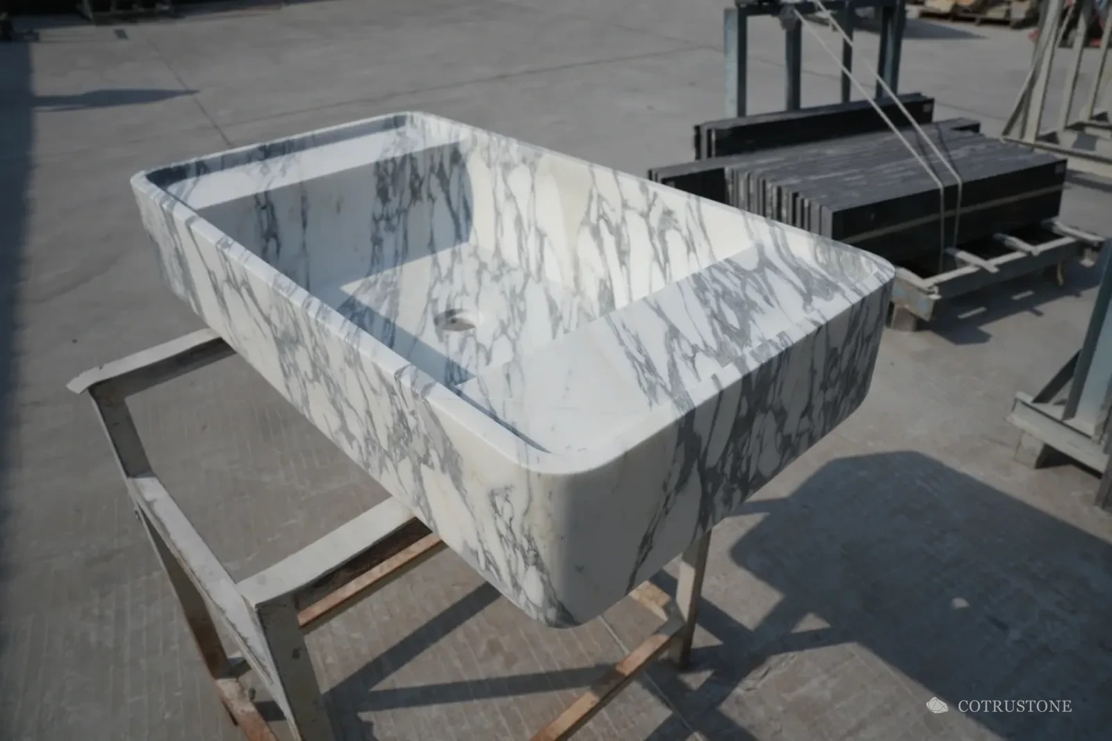 Rounded rectangular veined stone basin photographed on a support stand