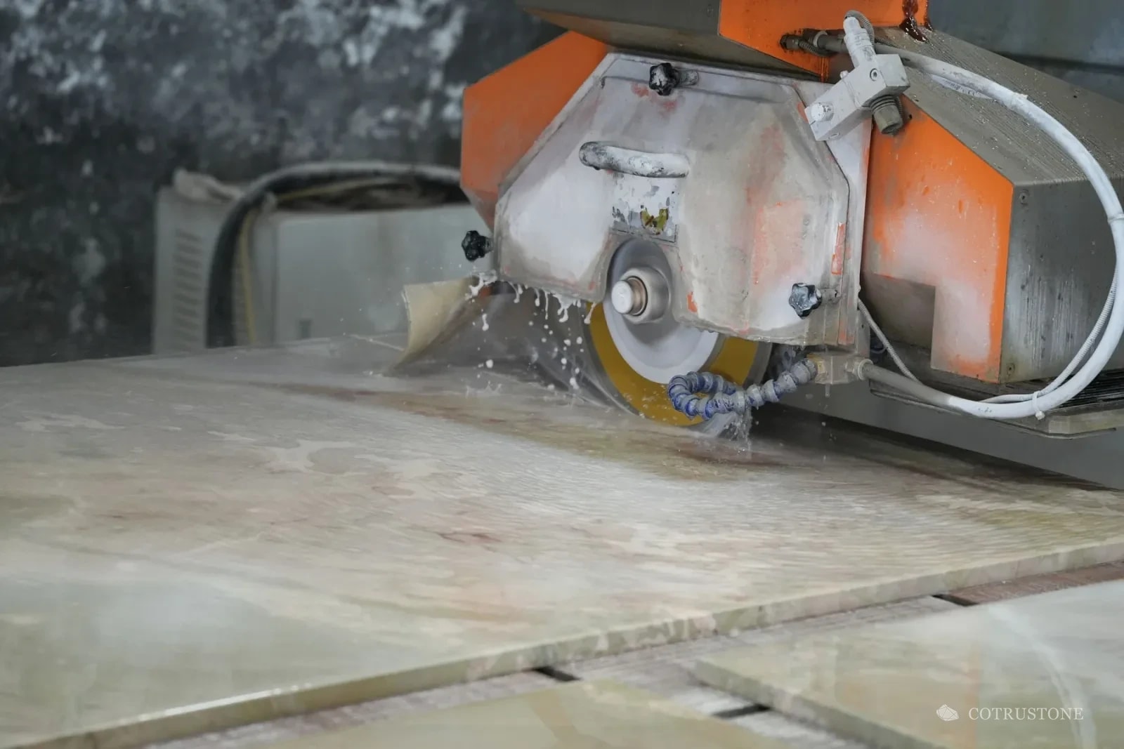 Wet cutting of a stone panel with the blade and water flow visible