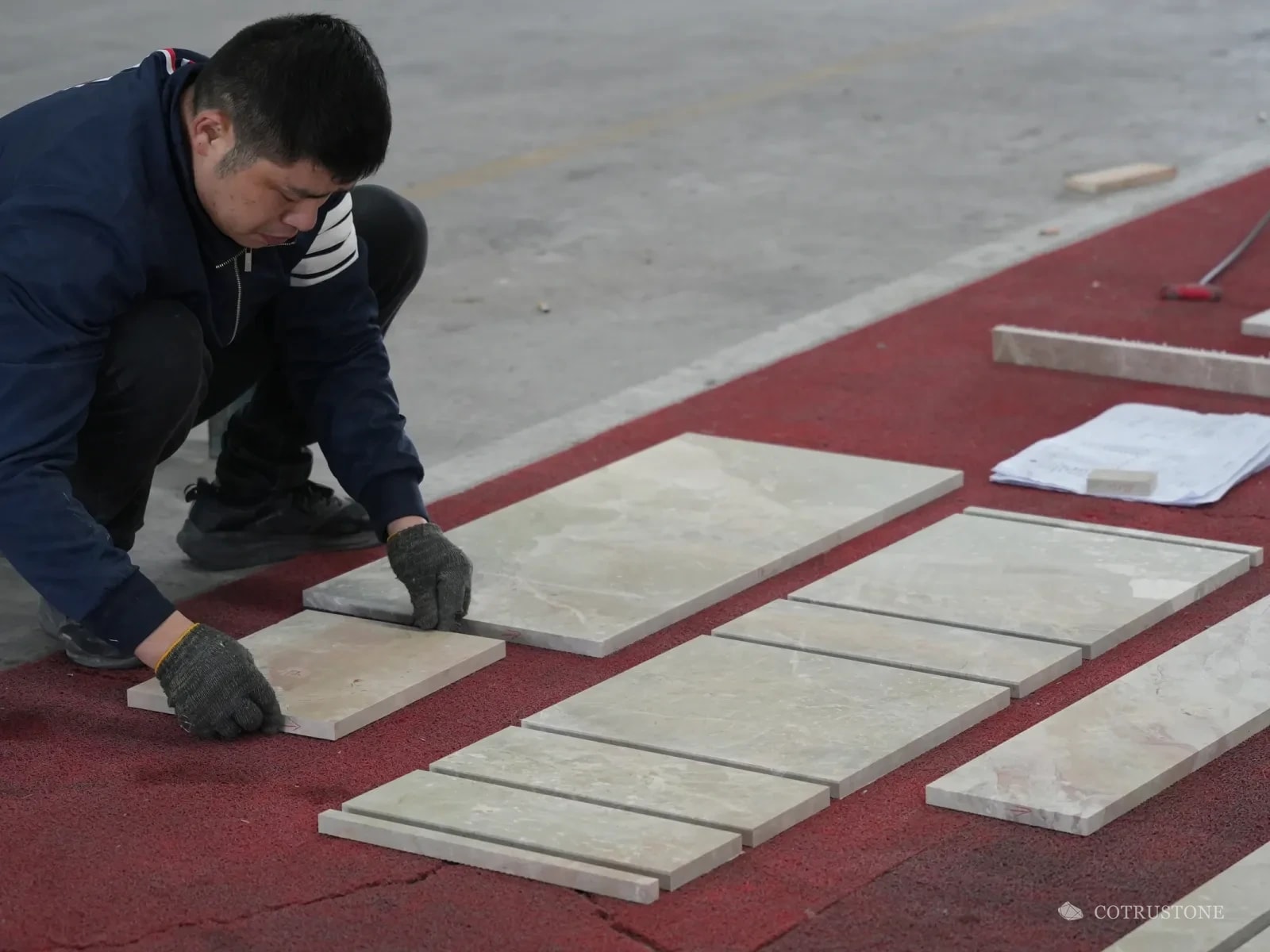 Worker in gloves laying out cut marble pieces on the workshop floor