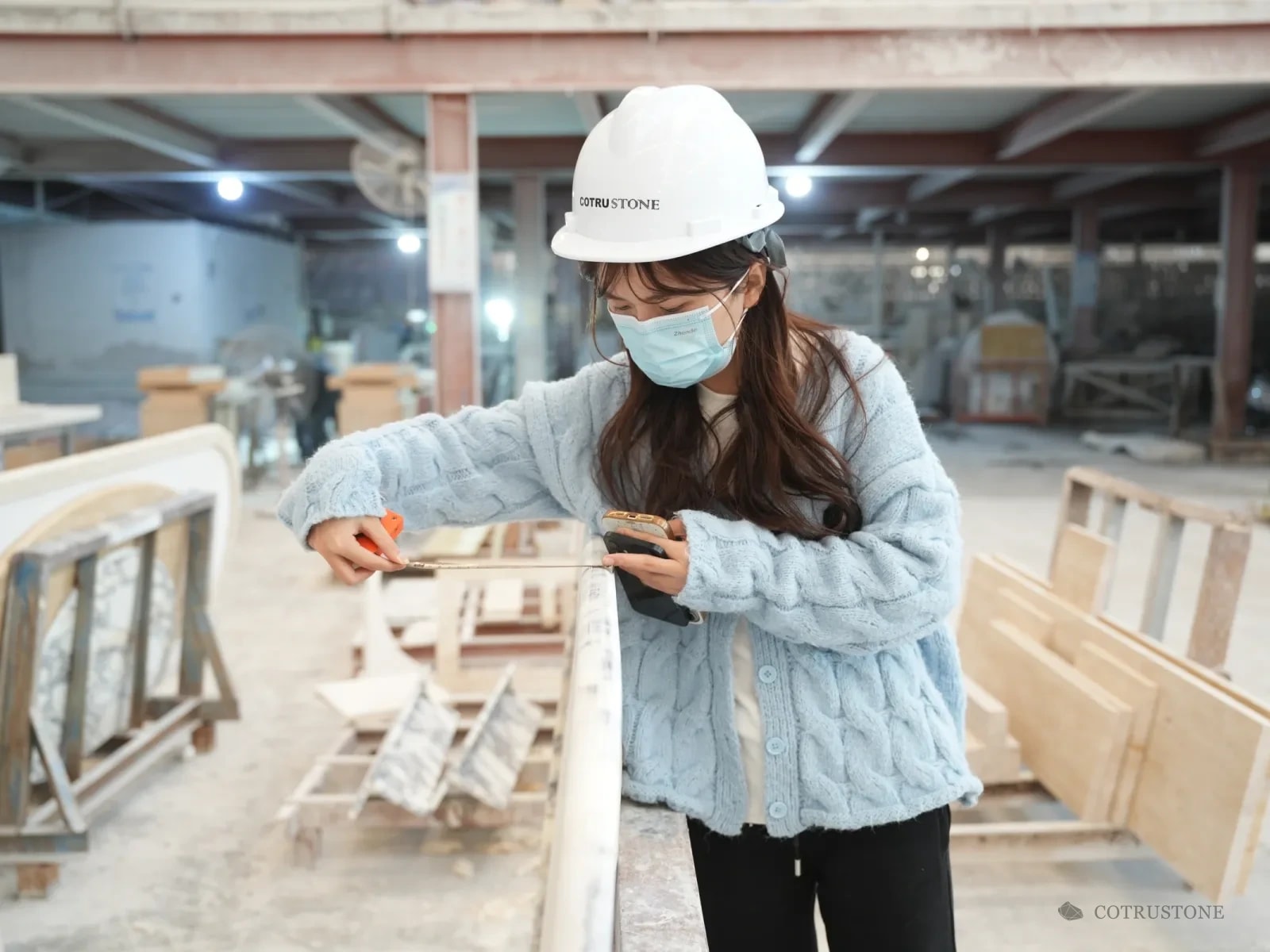 Inspector in a hard hat measuring a stone piece on the workbench