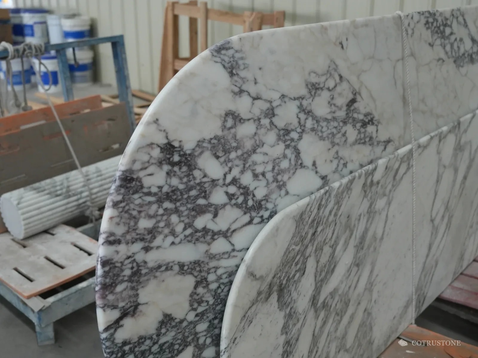 Finished white marble table top with purple veins standing on a rack in the workshop