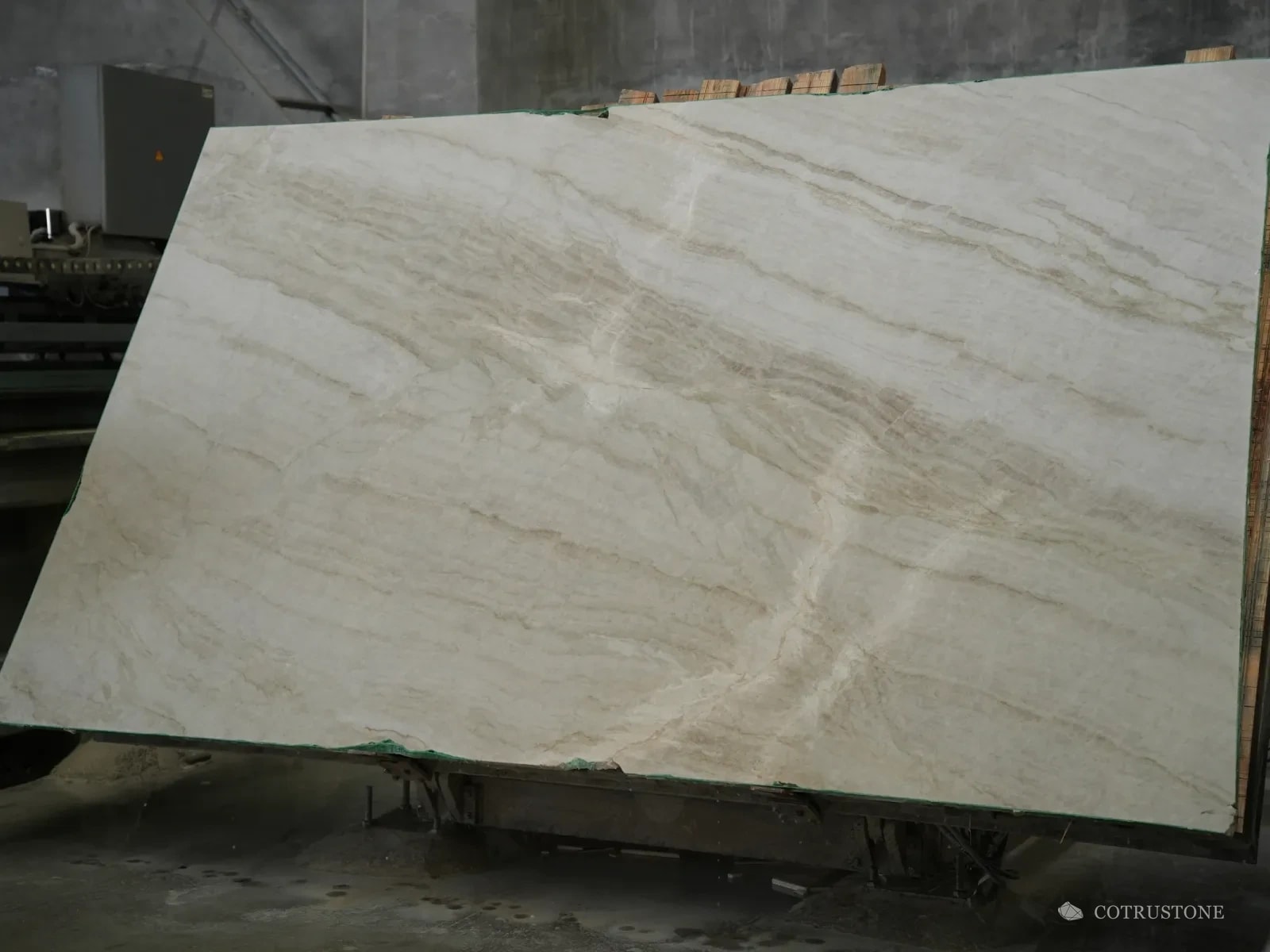 Cream marble slab with soft gold veins standing on an A-frame in the slab yard