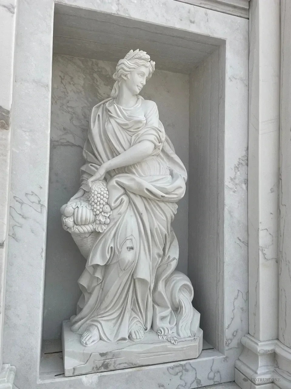 Carved stone figure framed by a marble niche