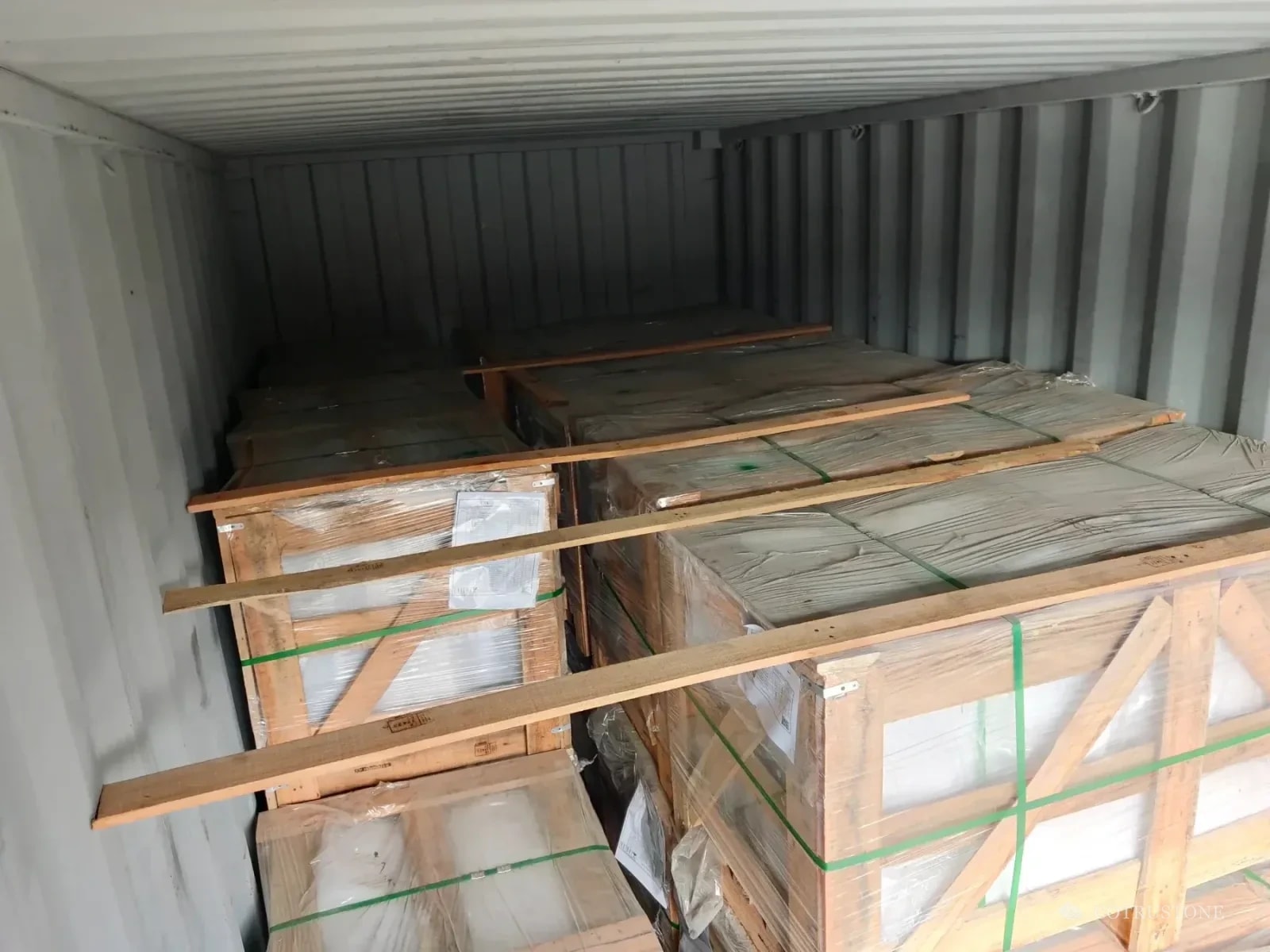 Wrapped stone crates inside a shipping container with timber cross bracing