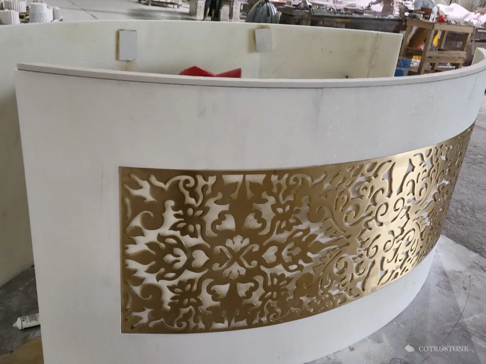 The curved reception counter from the side, showing the brass panel following the curve of the stone