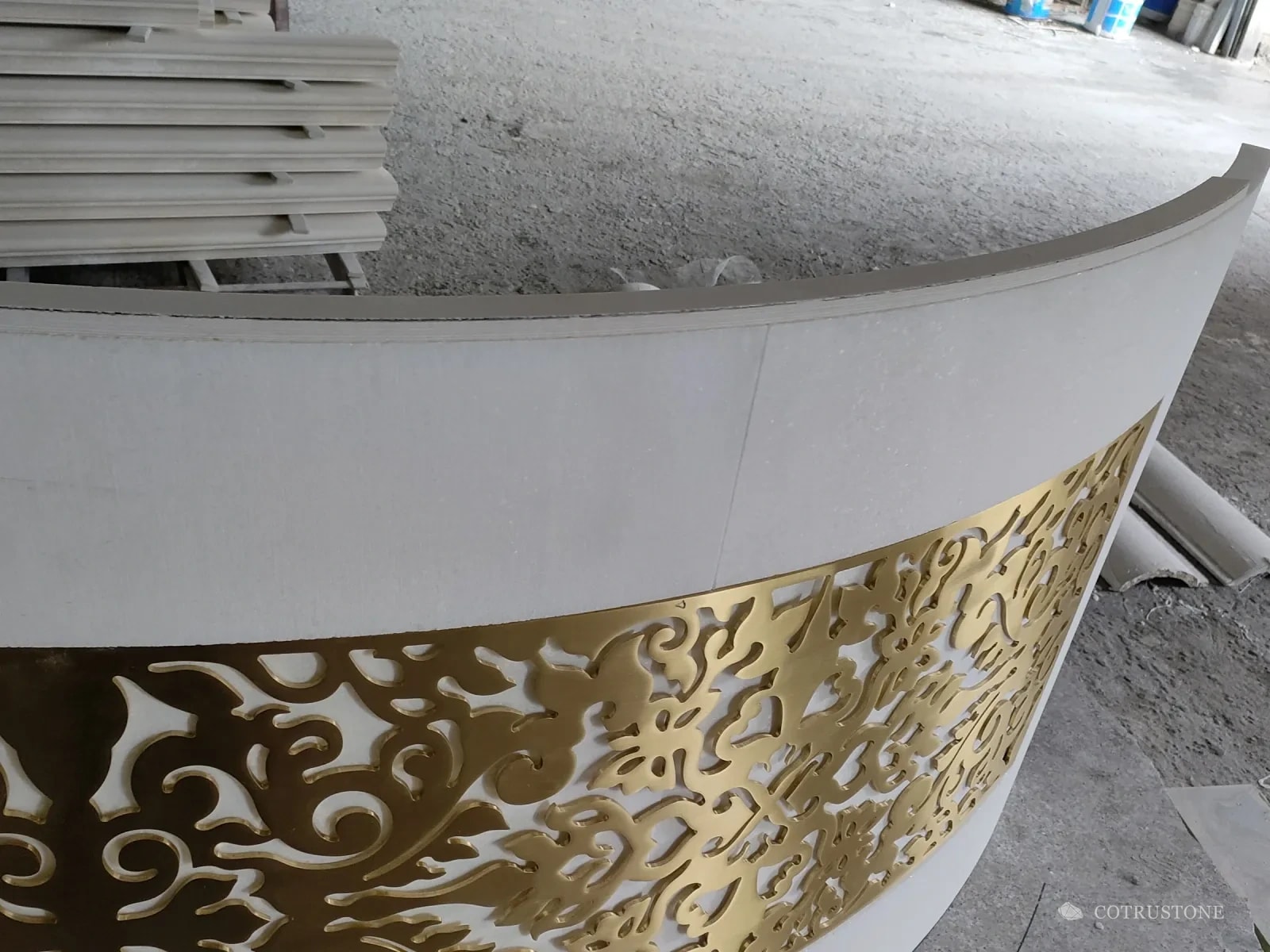 Close-up of the waterjet-cut brass scroll panel set into the curved white marble