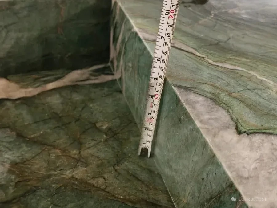 Tape measure inside the green veined stone basin during a bowl-depth check