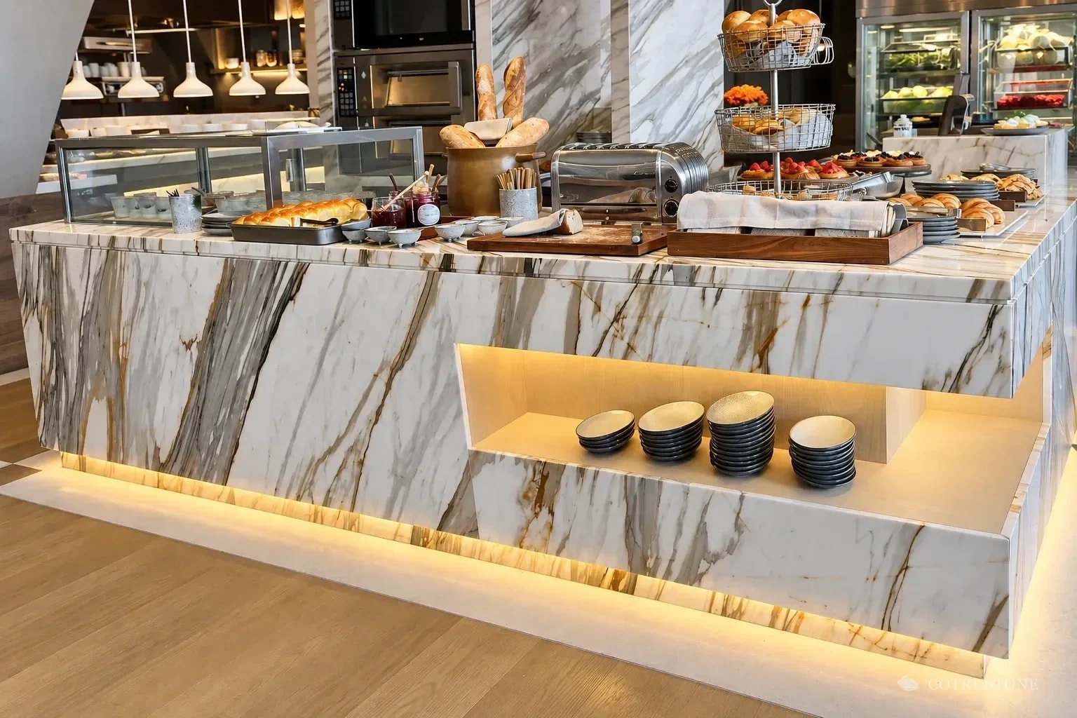 Marble buffet counter with veined apron, illuminated recessed niche and warm base lighting