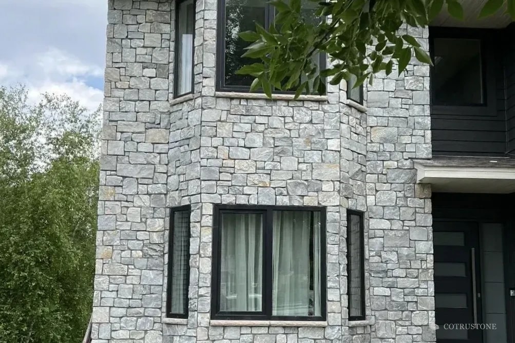 Grey stone wall cladding around the windows of a residence