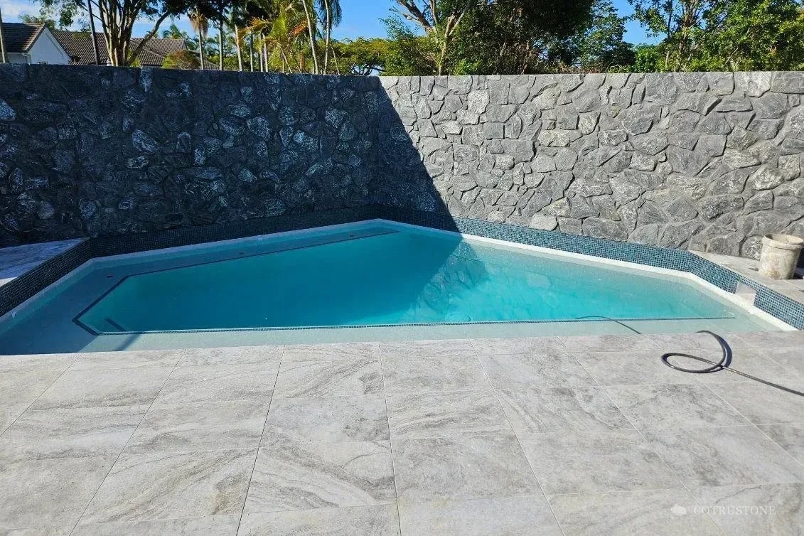 Muro de piedra y pavimento en un entorno junto a una piscina