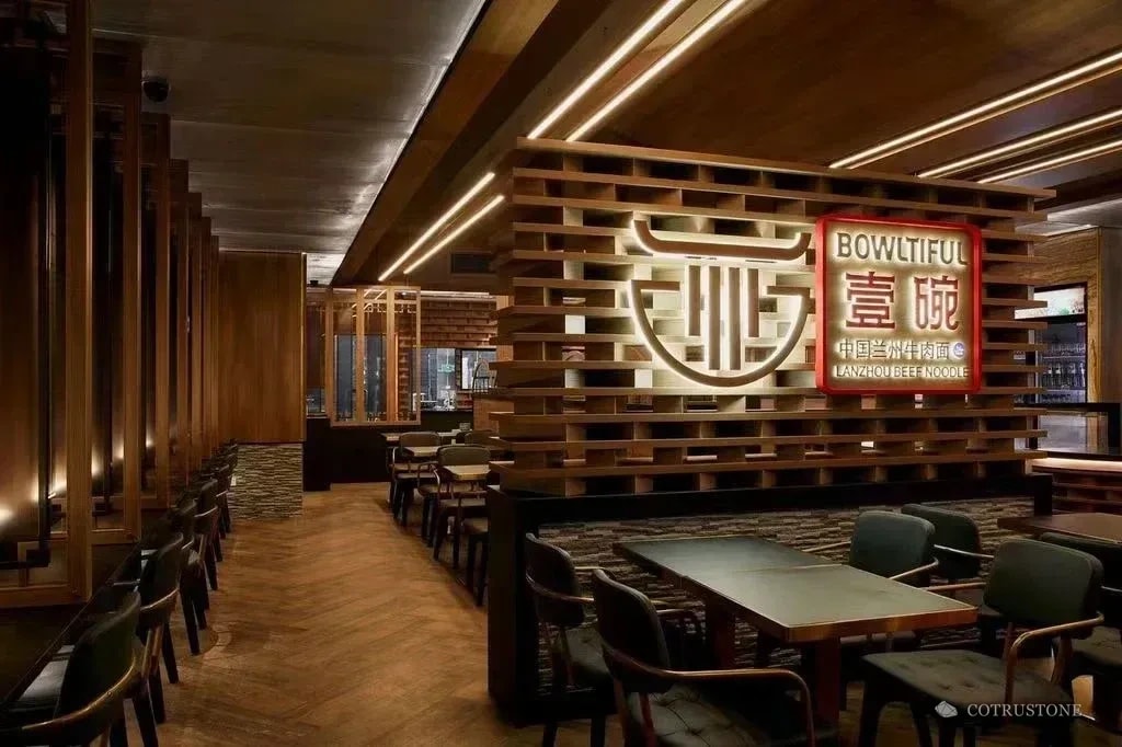 Warmly lit restaurant interior with stone wall finishes and timber detailing