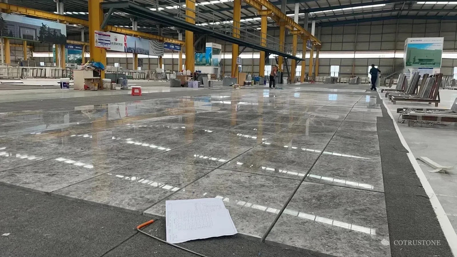 Large stone panel arrangement laid out across the workshop floor with a drawing in the foreground