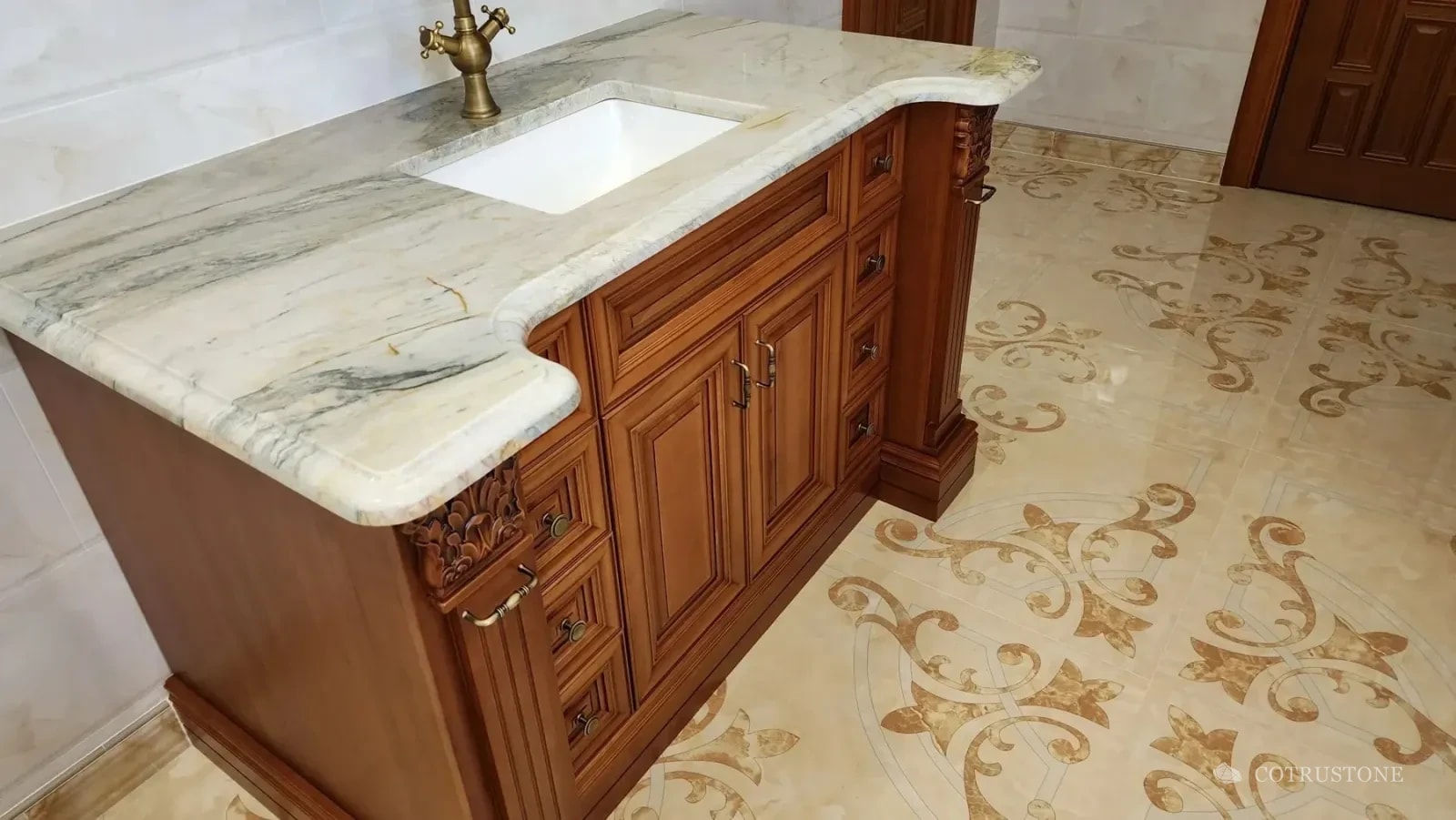 Natural stone kitchen counter with a shaped edge, undermount sink and curved cabinet junction