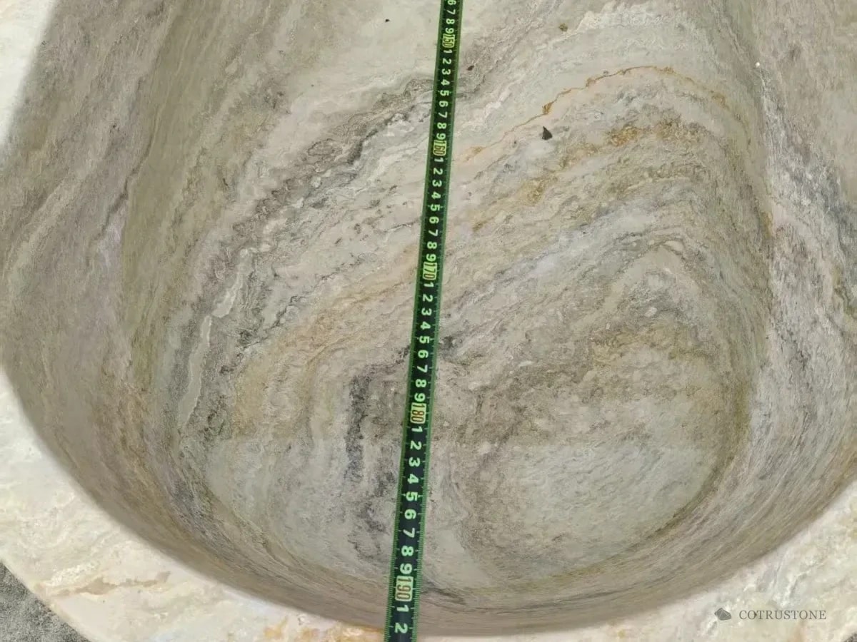 Tape measure across the inside of a silver-toned stone bathtub