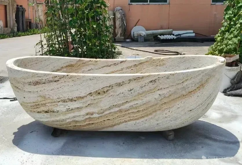 Silver-toned veined stone bathtub photographed outside the workshop