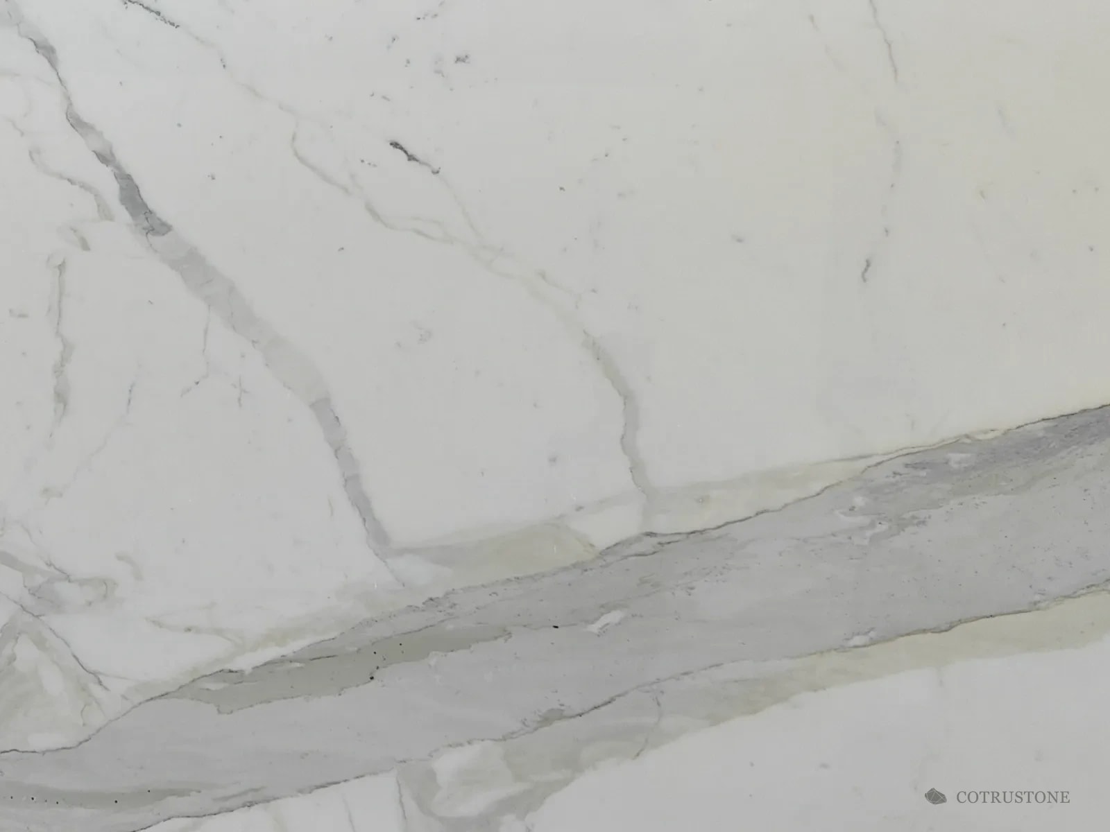 Mármol Calacatta con una banda ancha de gris y dorado pálido que cruza la placa