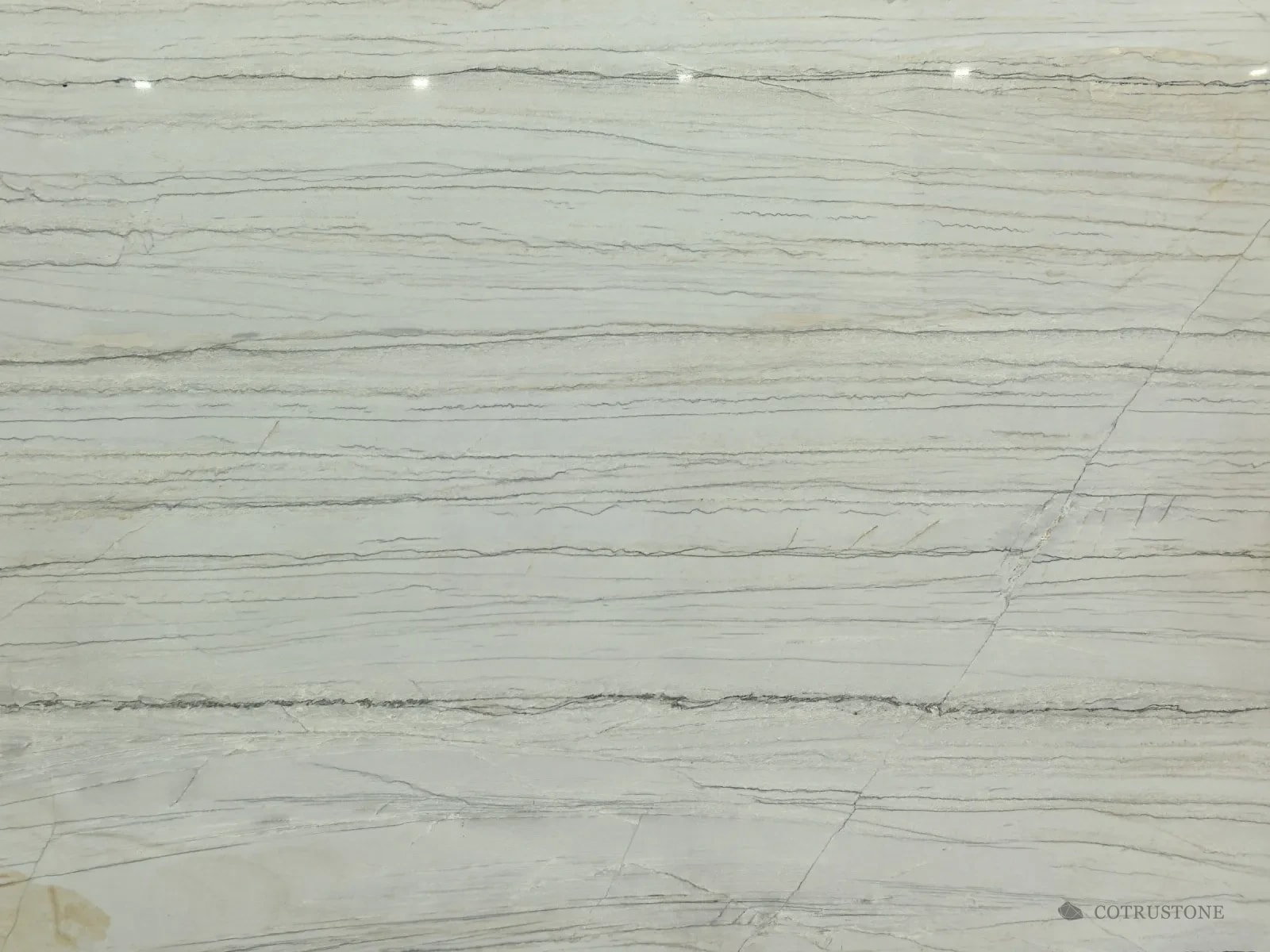 Close-up of Calacatta Macaubas quartzite: long parallel grey veins across a white ground