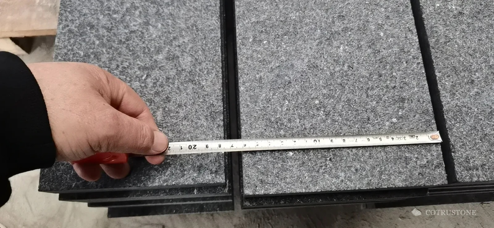 Measuring tape across a grey stone stair component