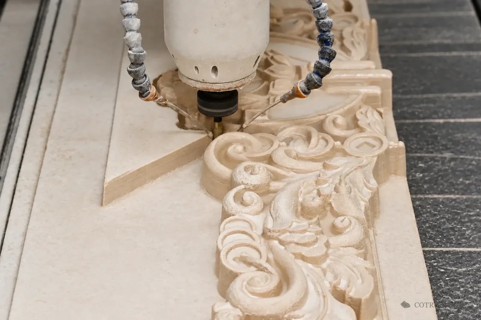 Machining head shaping a floral stone relief