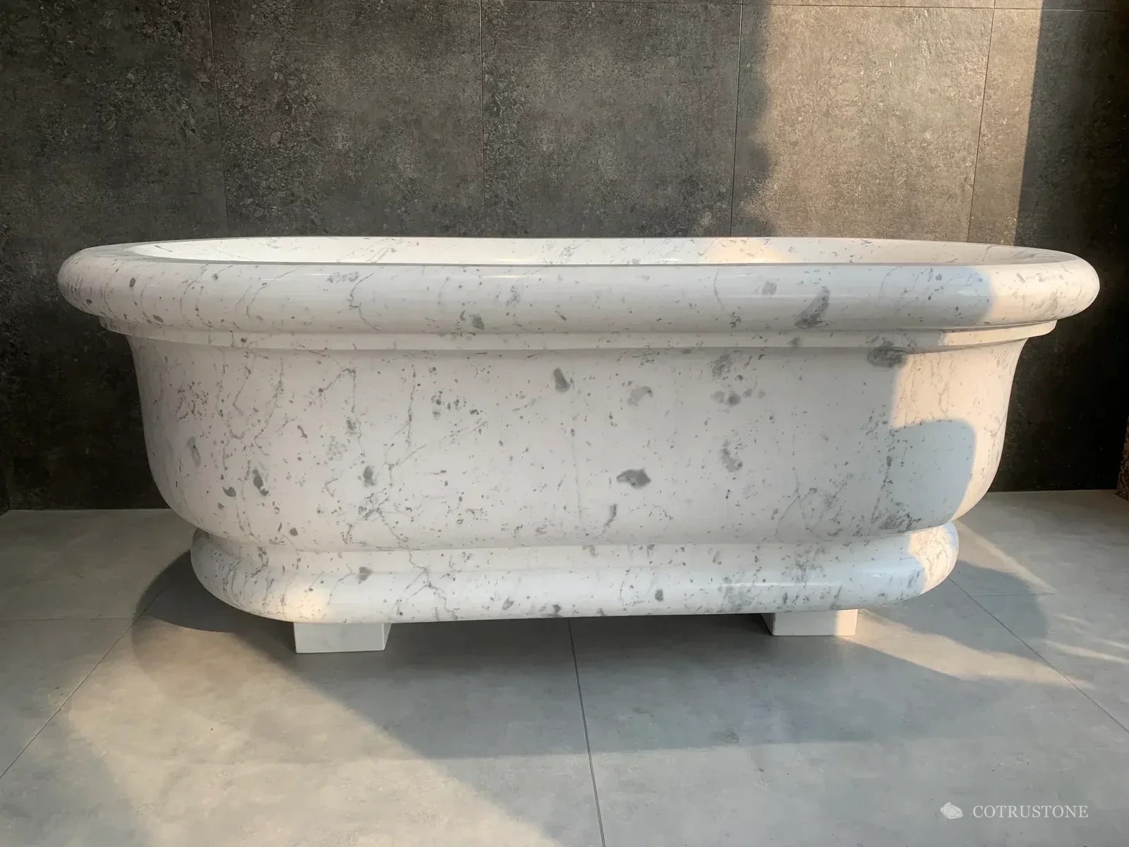 White stone bathtub showing pale veining and its side profile