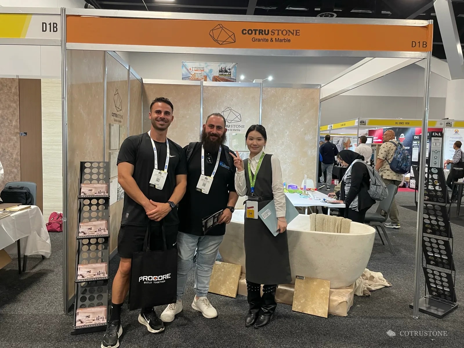 Cotrustone stand at Sydney Build with a stone bathtub, three people and the busy exhibition aisle