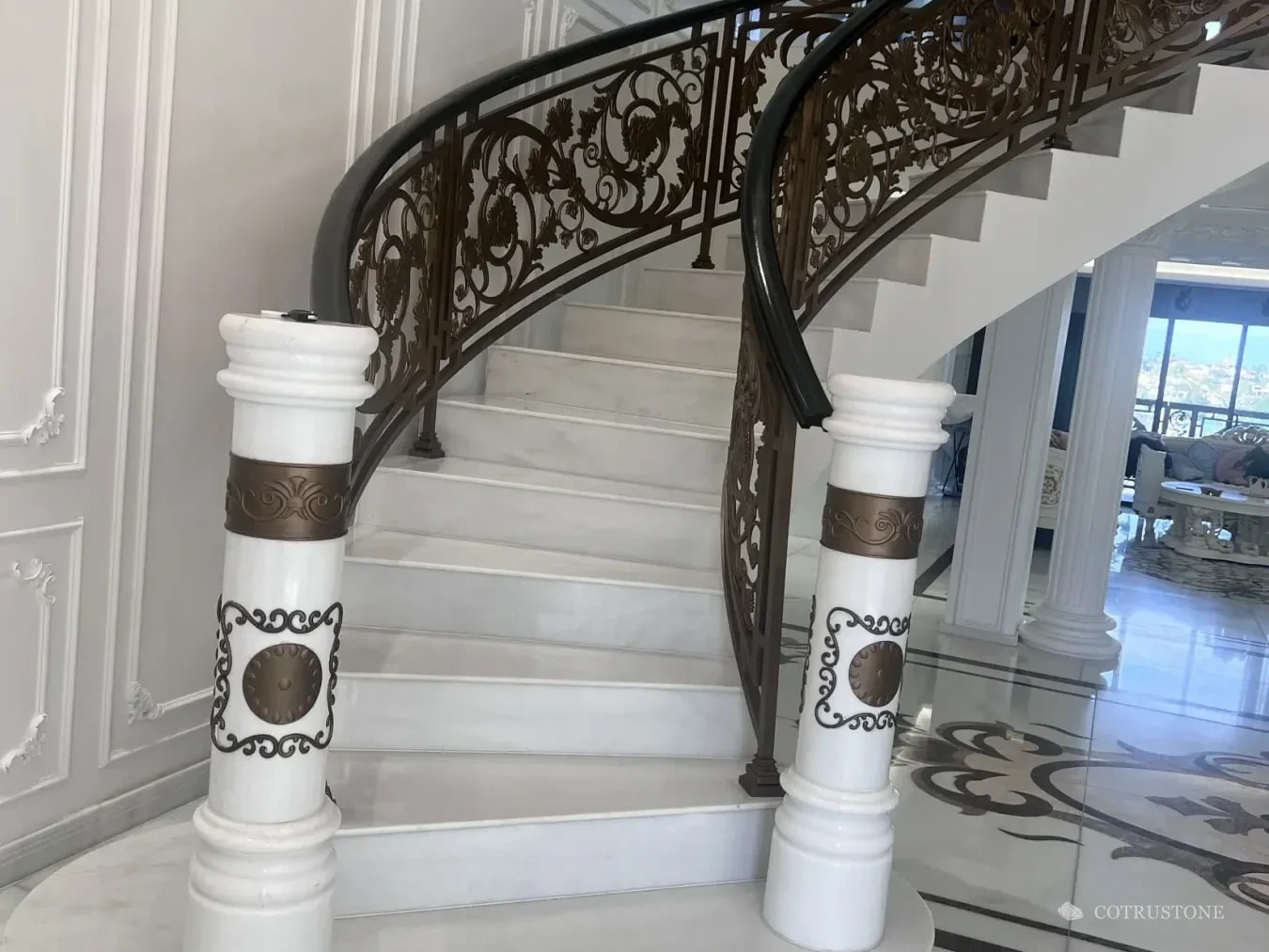 Curved stone stair with decorated newel posts and marble flooring photographed during a client visit