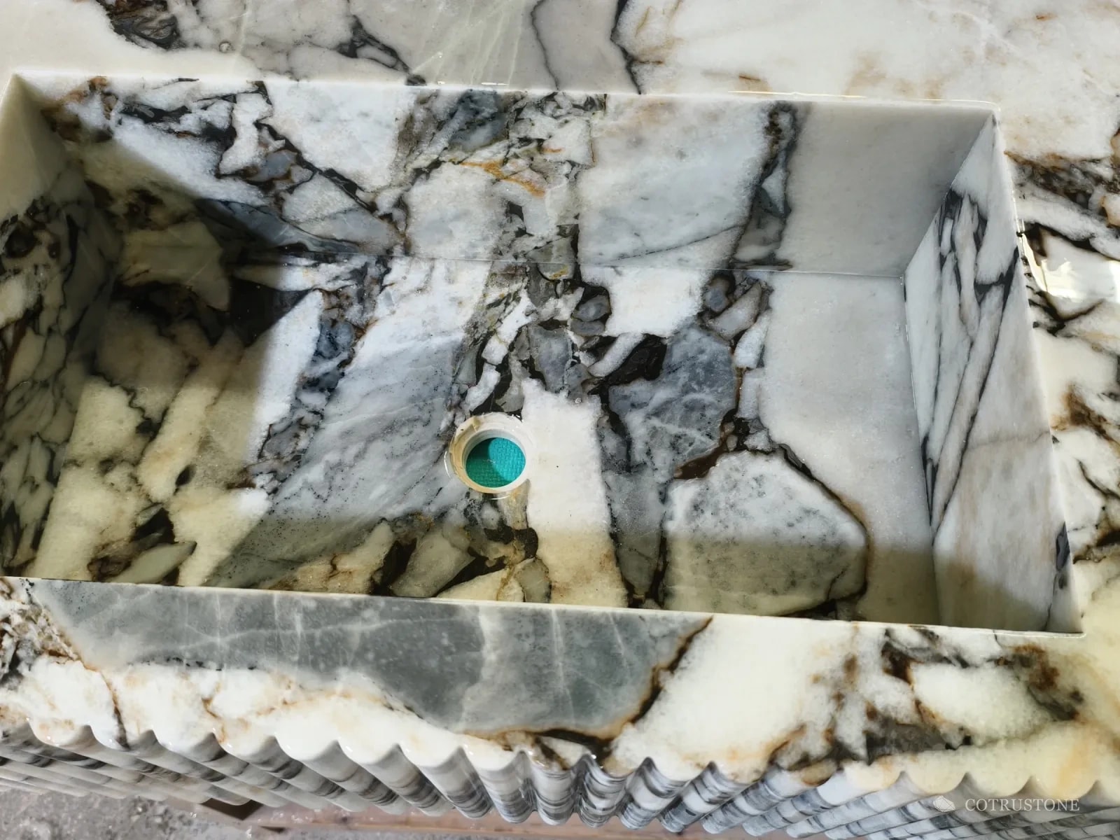 Rectangular basin cut into a boldly veined white marble top, with a fluted front below