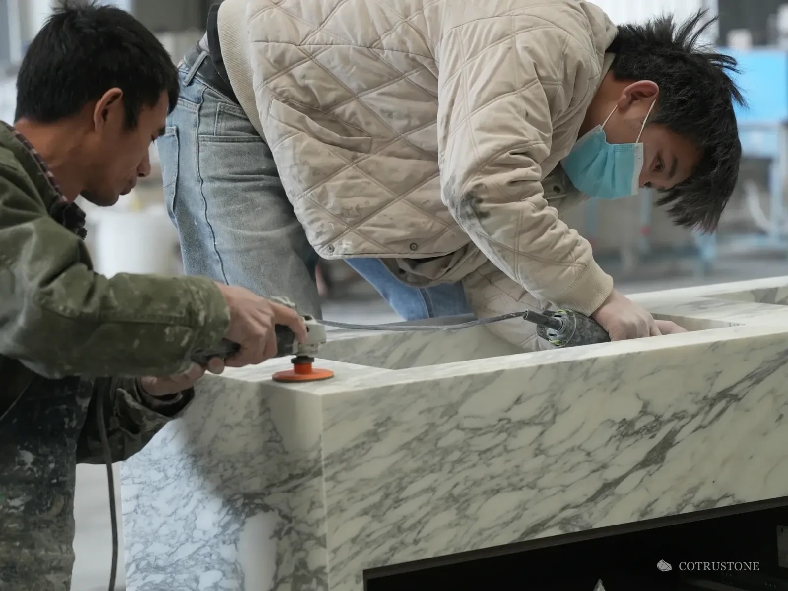 Two stone workers finishing a veined stone basin at the workbench