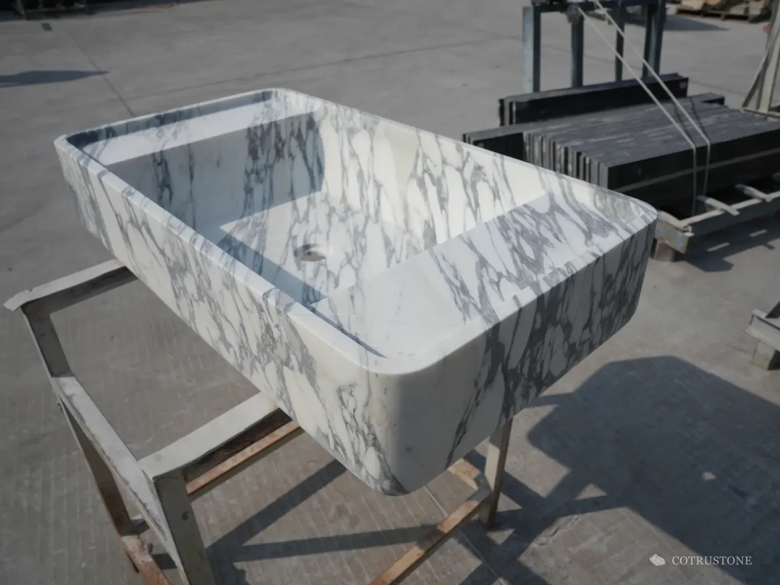 Rounded rectangular veined stone basin photographed on a support stand