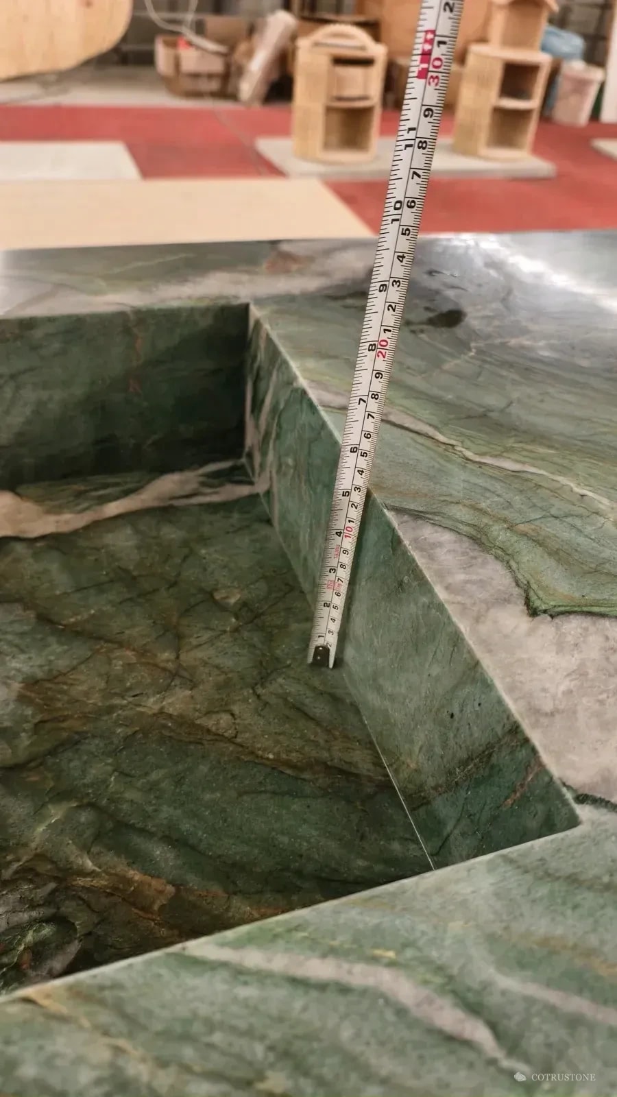Tape measure inside the green veined stone basin during a bowl-depth check