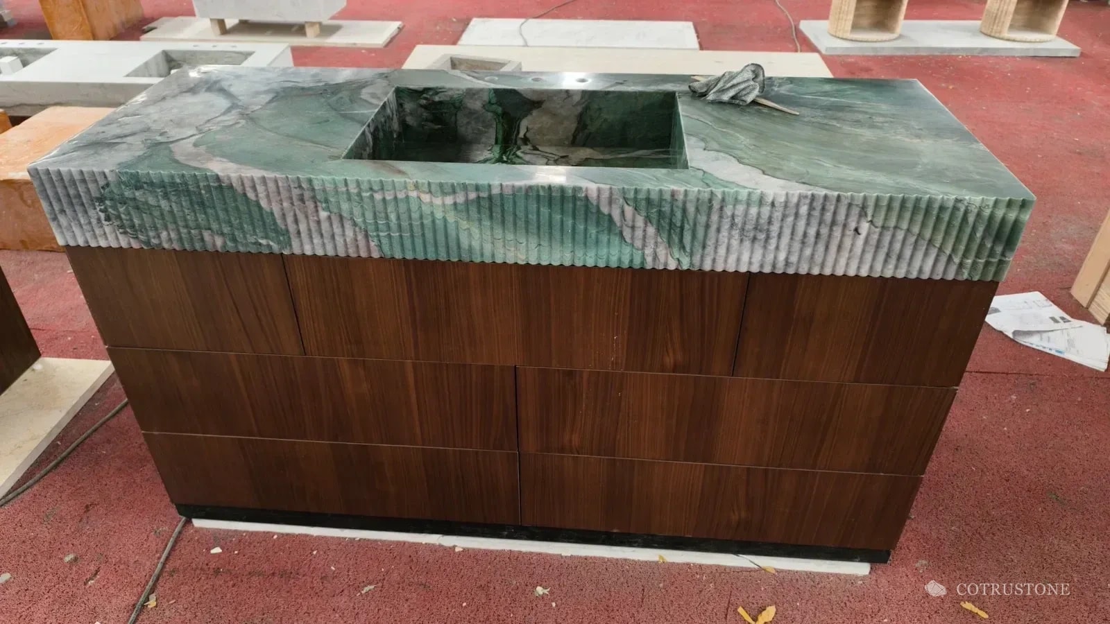 Green veined stone integrated basin with a reeded front above a dark wood cabinet in the workshop