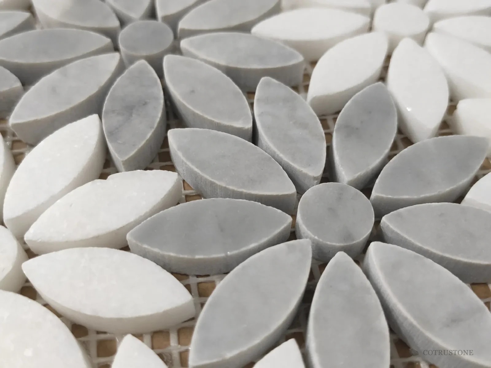Close-up of a daisy mosaic: white and grey stone petals around round centres