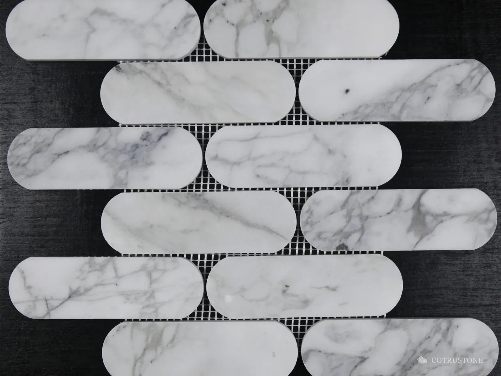 Long rounded mosaic pieces in white stone with grey veins, laid in staggered rows