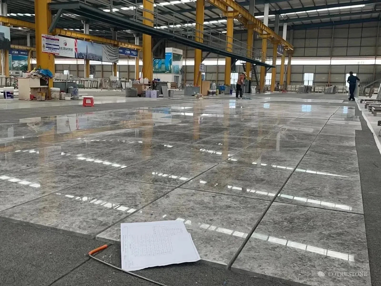 Large stone panel arrangement laid out across the workshop floor with a drawing in the foreground
